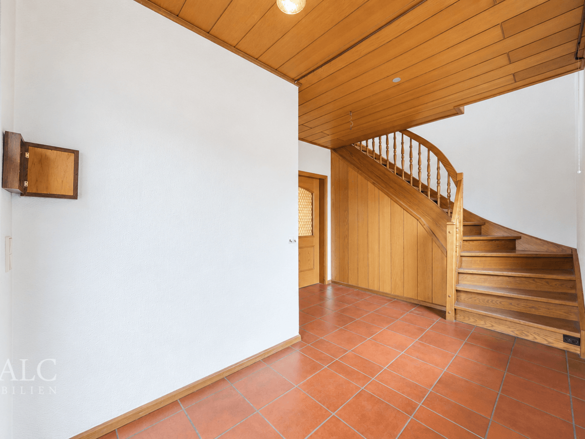 Heller Eingangsbereich mit Holztreppe und Terrakottafliesen